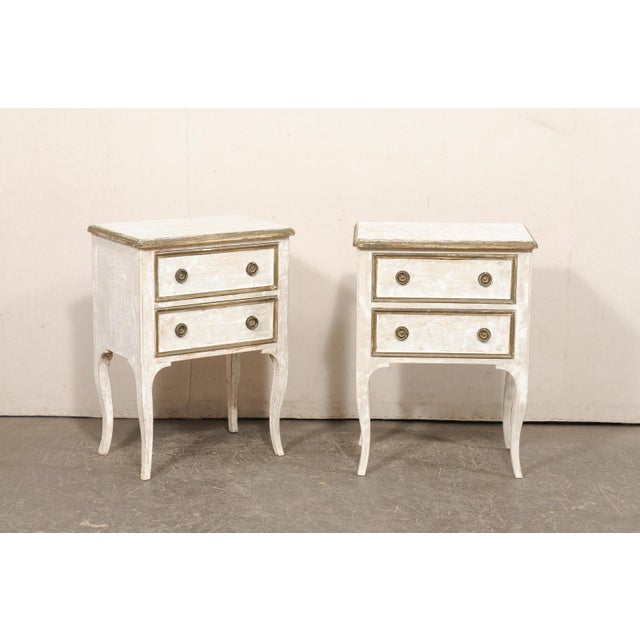 A Italian pair of painted wood, raised, two-drawer side chests from the mid 20th century. This vintage pair of end tables...