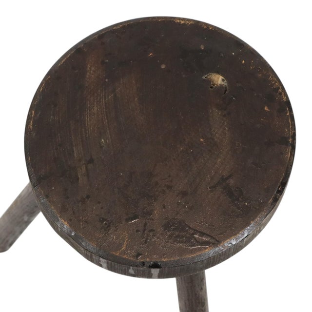 Vintage wooden three-legged stool (or milking stool) made of solid stained wood; a handmade 20th-century piece with a...