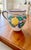 The image showcases a beautiful, handcrafted ceramic pitcher, from Sicily, Italy. The following information is known:...