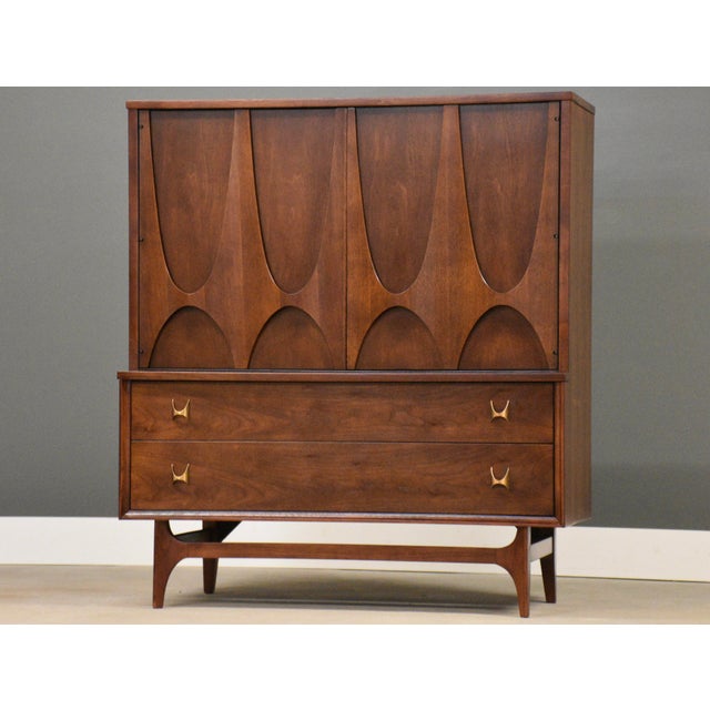 A mid century modern walnut six drawer tall dresser with swooping walnut and brass arch details made by Broyhill Brasilia....
