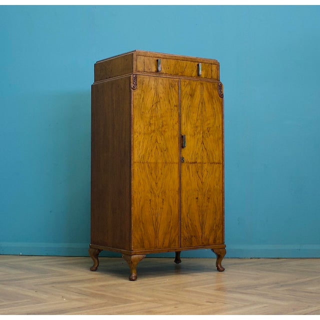 Art Deco walnut tallboy with figured veneer and shaped legs. Single top drawer. Double doors open to two internal drawers...