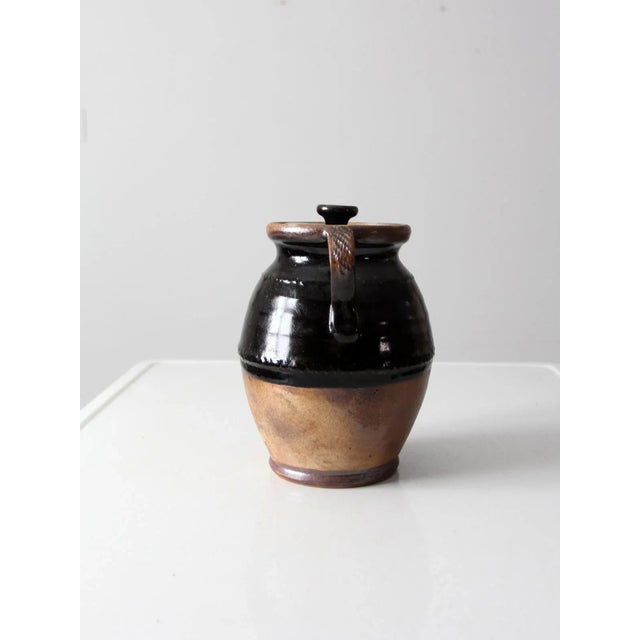 This is a vintage studio pottery jar dated 2002 and signed the artist, John Tiller. The hand-crafted jar features etched...