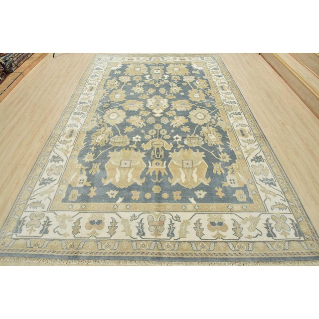 This traditional Oushak rug is hand-knotted with an all-wool pile on a cotton foundation. This rug is new and in excellent...