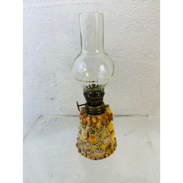 This vintage miniature oil lantern features a clear glass chimney rising from a timeworn brass burner with a side-adjust...