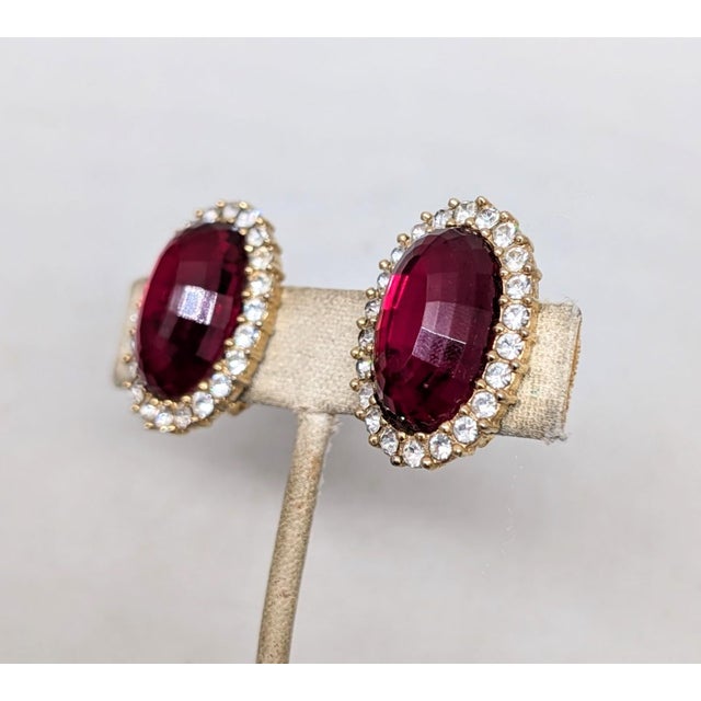 Circa 1960s oval goldtone with oval disco-like cut faux-garnet surrounded by small round clear rhinestones clip earrings....