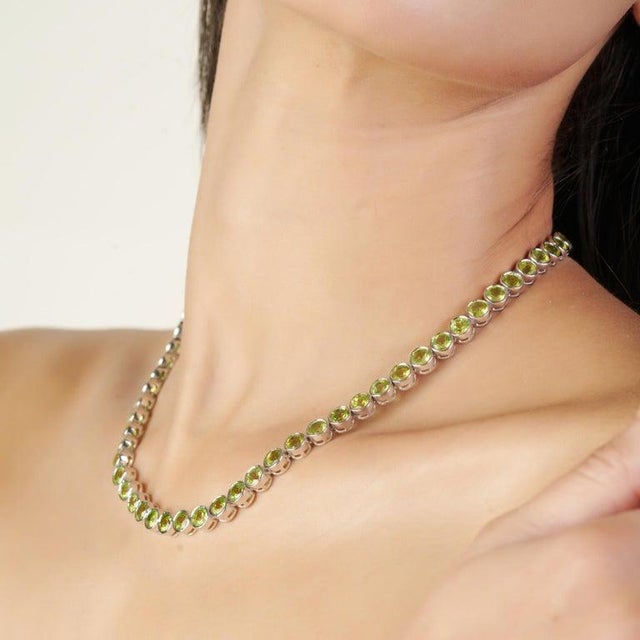 This elegant tennis necklace is crafted in luminous 925 sterling silver and set with 65 natural peridot gemstones, each...