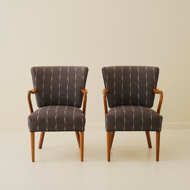 Pair of Danish armchairs dating from the 1940s–50s, each with an oak frame, sculpted armrests, and upholstered seat and...