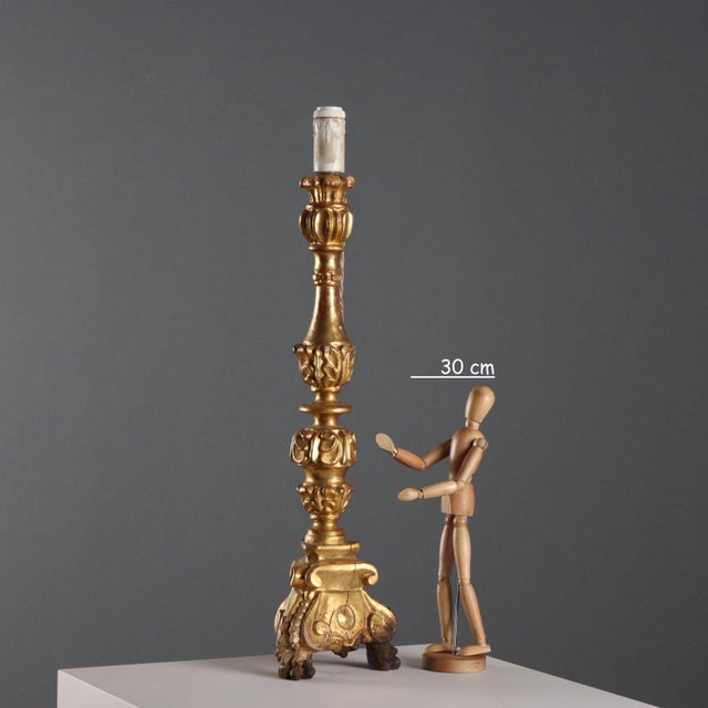This carved and gilded wooden candelabra from Italy in the late 19th century exemplifies the decorative craftsmanship of...