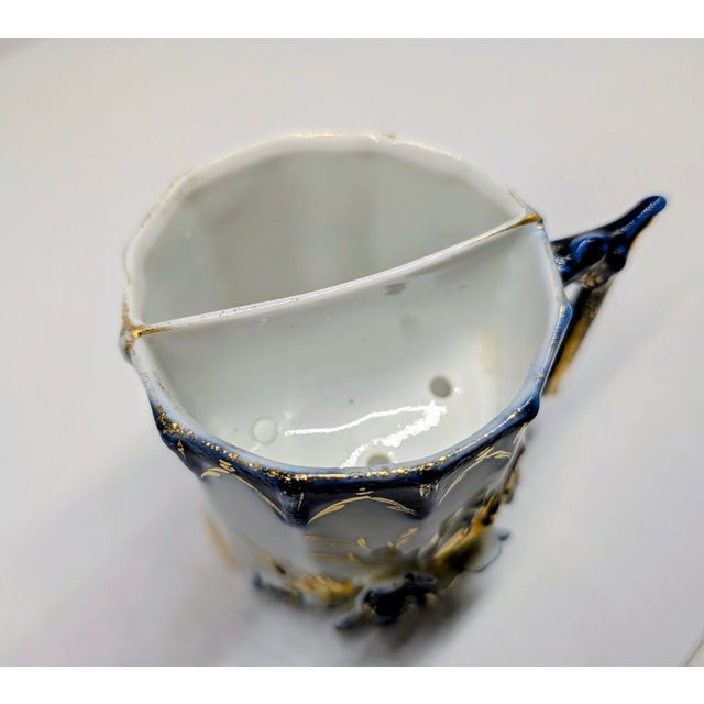 A finely detailed antique porcelain shaving mug featuring raised floral relief decoration accented with deep cobalt blue...