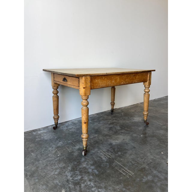 A quintessential piece of 19th-century English countryside charm, this antique pine table features a pale warm surface and...