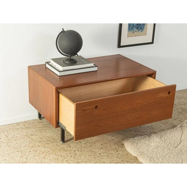 Classic chest of drawers from the 1960s in Scandinavian design. Corpus in teak veneer with a drawer and new square steel...