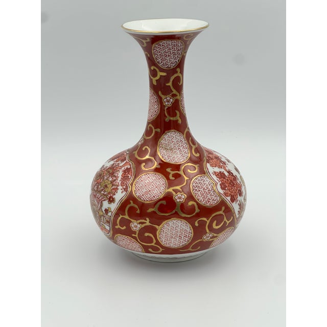 A richly detailed Gold Imari porcelain vase featuring ornate medallions, floral motifs, and a scenic panel rendered in...