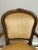 This French Louis XV-style fauteuil armchair features ornate hand-carved wood and champagne color velvet upholstery....