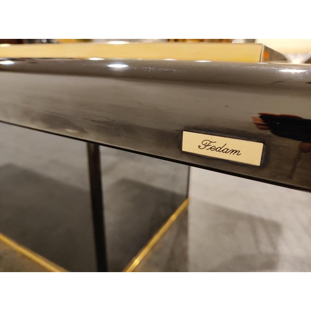 Unique coffee table that, with a twist of the knob, reveals a hidden bar compartment. The coffee has a brass and mirrored...