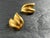 Polished gold-tone earrings designed in a fluid double-leaf motif with softly curved forms and a high-shine finish....