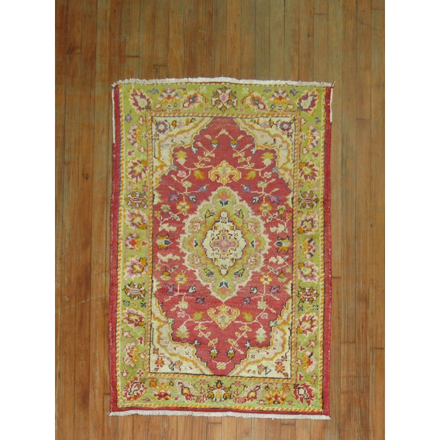 A mid 20th century Turkish rug with a colorful red and green palette Measures: 2'10'' x 4'1''.