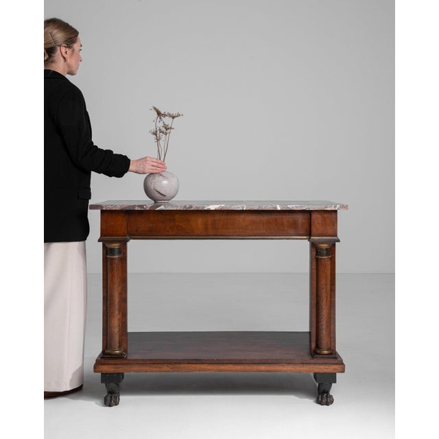 Here is a table, its dark mahogany, marble top visible, brass ring the first thing to catch the eye. Originating in France...