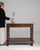 Here is a table, its dark mahogany, marble top visible, brass ring the first thing to catch the eye. Originating in France...