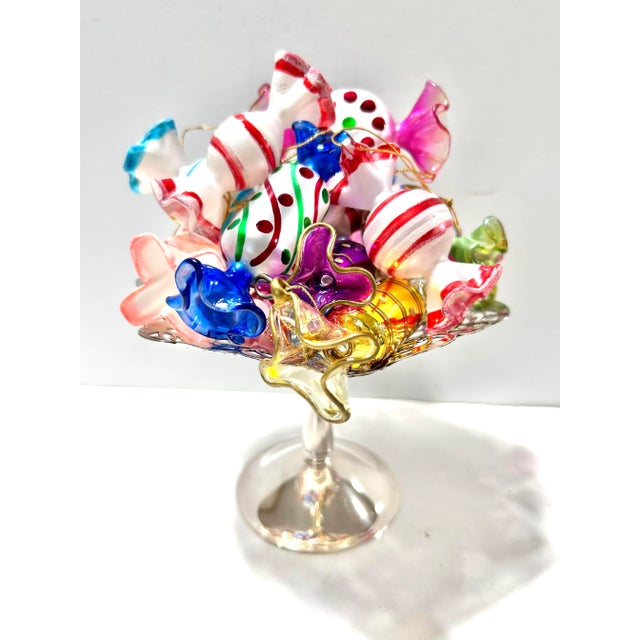 A colorful set of 13 vintage hand-blown glass Christmas ornaments shaped like wrapped candies, each decorated with bright...