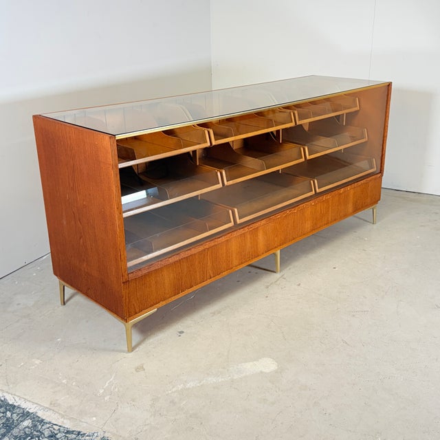 Beautifully crafted counter from the 1960s. The frame is made of solid oak and stands on six gold-colored steel legs with...