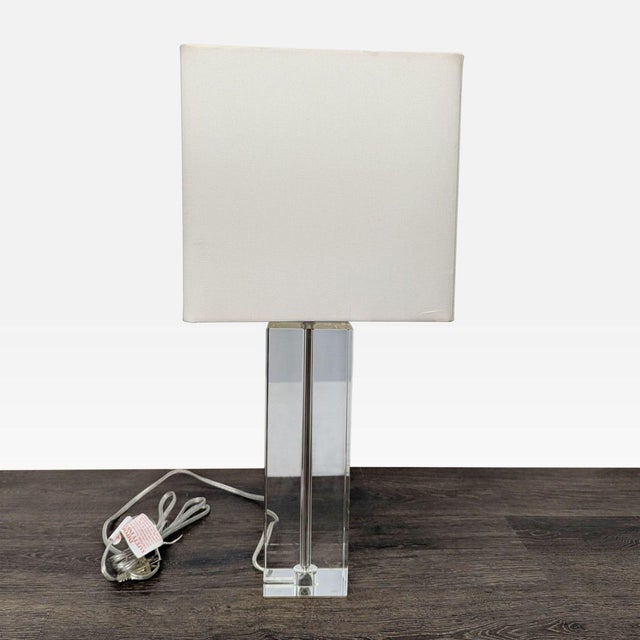 This modern table lamp features a lead crystal base and a simple white rectangular shade. Its clean, minimalist design is...