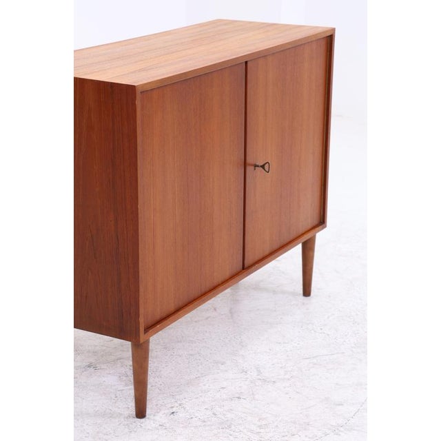 Vintage teak chest of drawers by Musterring from the 1960s. The clean front design, the slender tapered legs and the...