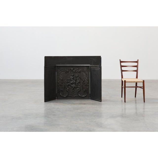 A richly detailed 18th‑century French Rococo fireback in solid cast iron, featuring an ornate central relief with...
