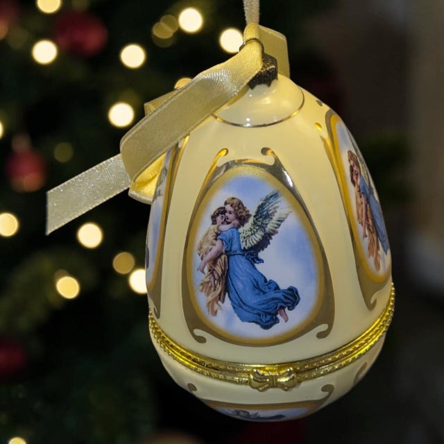 The Mr. Christmas Valerie Parr Hill Musical Egg Angels Hinged Trinket Box Ornament is a beautifully crafted porcelain...