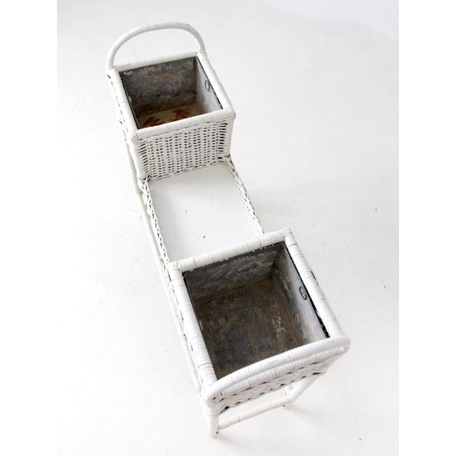 This antique white wicker plant stand is a charming display piece for indoor or covered outdoor spaces. It features two...