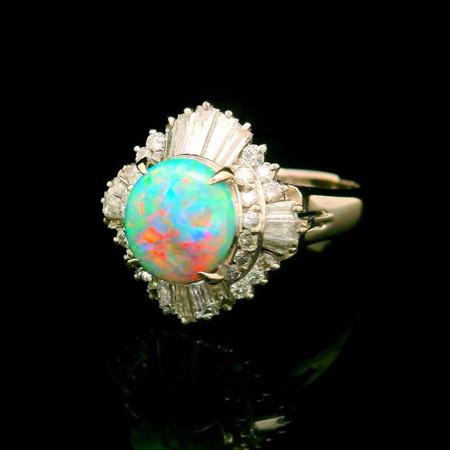 A striking opal gemstone commands attention at the heart of this ring. The opal, weighing 1.35 carats, in an oval shape...