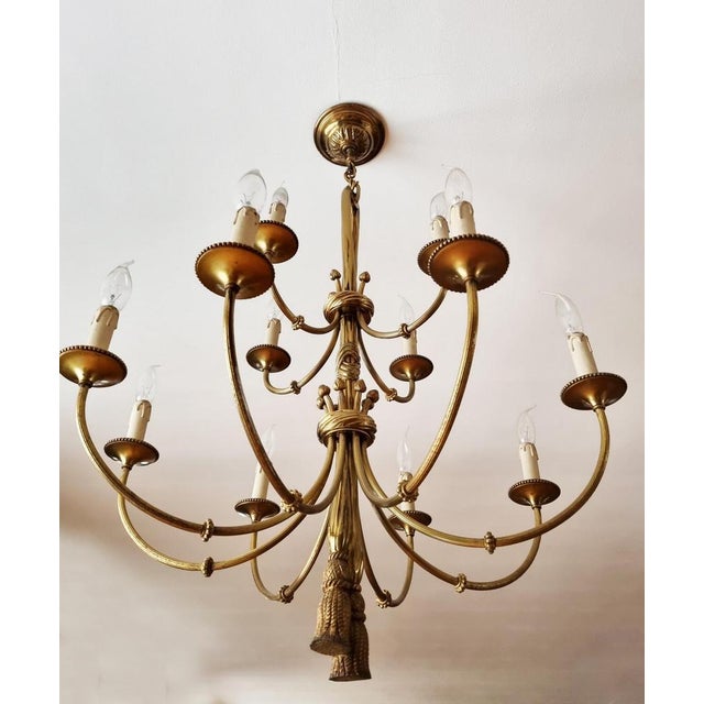 Amazing solid bronze chandelier decorated with tassels, knots and ribbons. Its 12 slender arms with bobeches with beaded...