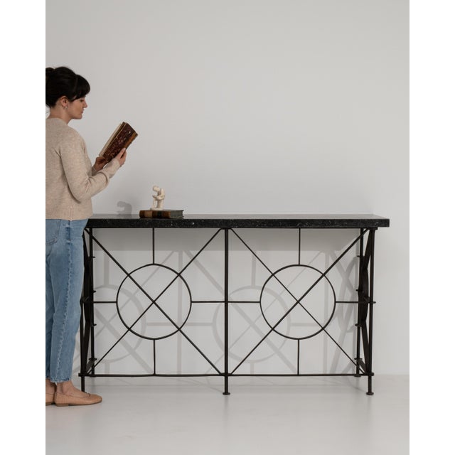 A 19th century French console table crafted in wrought iron and topped with a blue stone surface. The design reflects...
