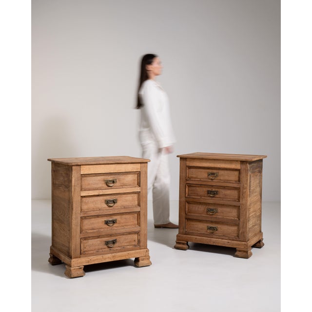 A well-matched pair of oak chests featuring multiple drawers and brass hardware that adds contrast and refinement. The...