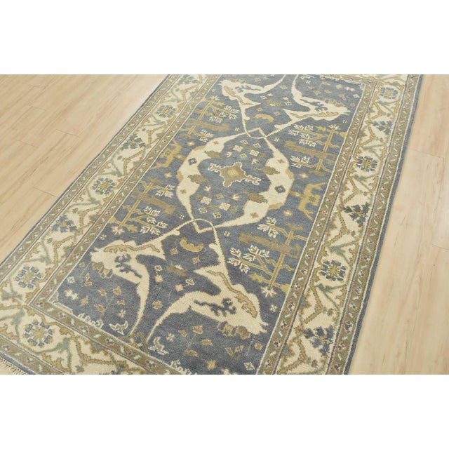 A modern tribal Oushak rug hand-knotted with an all-wool pile on a cotton foundation. This oriental rug features a central...