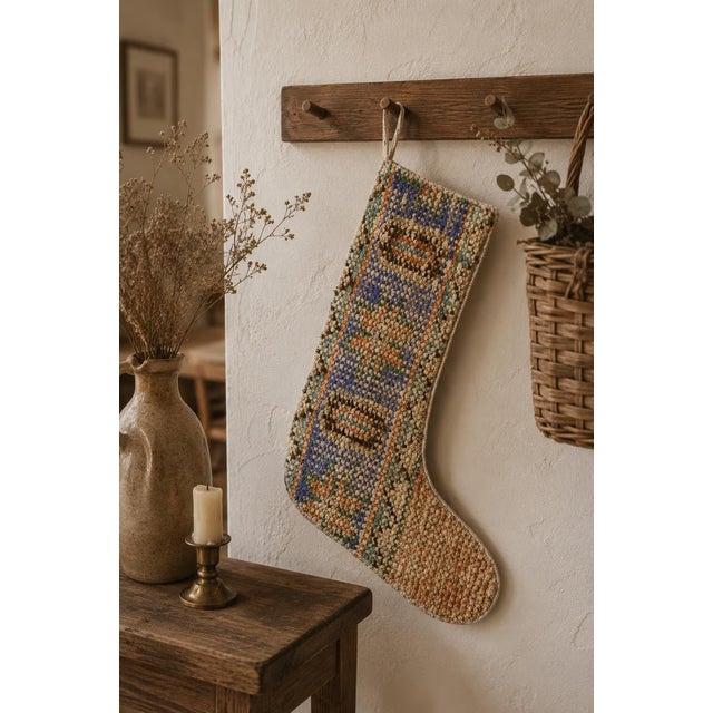 This vintage wool kilim stocking stands out with a striking periwinkle blue center band, framed by rust orange and sage...