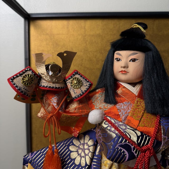 This Japanese warrior figure is presented in a glass display case with a black lacquered wooden frame and a front-opening...