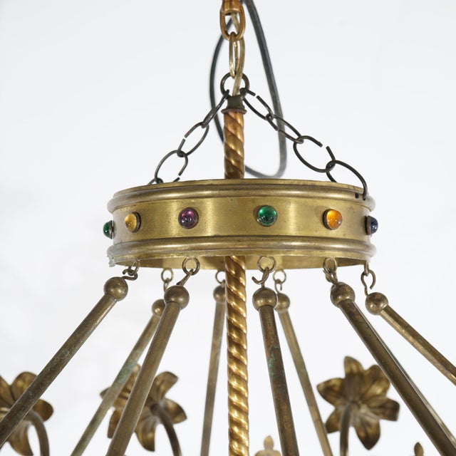 An antique French style chandelier offers brass frame in Fleur-de-Lis form having twelve floral form arms terminating in...