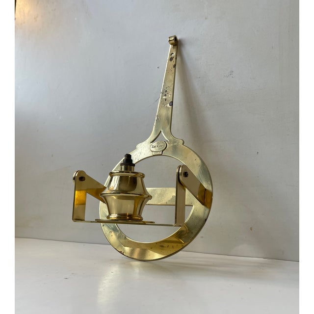 Nautical - maritime wall hung oil lamp sconce fashioned from brass. It features a tilting mechanism so that the flame is...