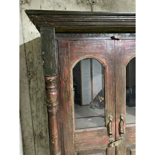 Lovely vintage English colonial painted cabinet with glass. It features a nice patina, teak wood doors, and great...
