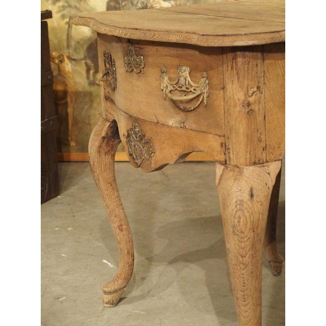 This charming oak console table was hand carved in the Netherlands during the 1700’s. The shaped top has quarter round...