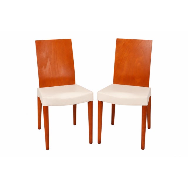 A pair of dining side chairs by Philippe Starck for Kartell. Tan molded polypropylene seat, beechwood legs and wooden...