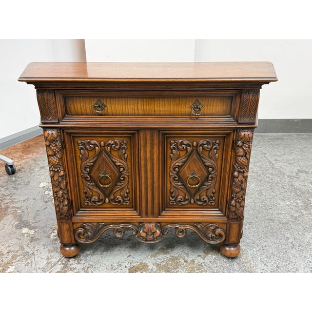 Design Plus Gallery presents a 1920's Tudor Revival Carved Walnut Buffet Cabinet by Empire Manufacturing Company. This...