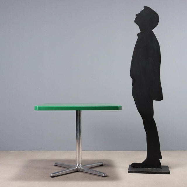 Square-shaped table with 4 foldable sections, aluminum base and plastic top. This piece is attributed to the mentioned...