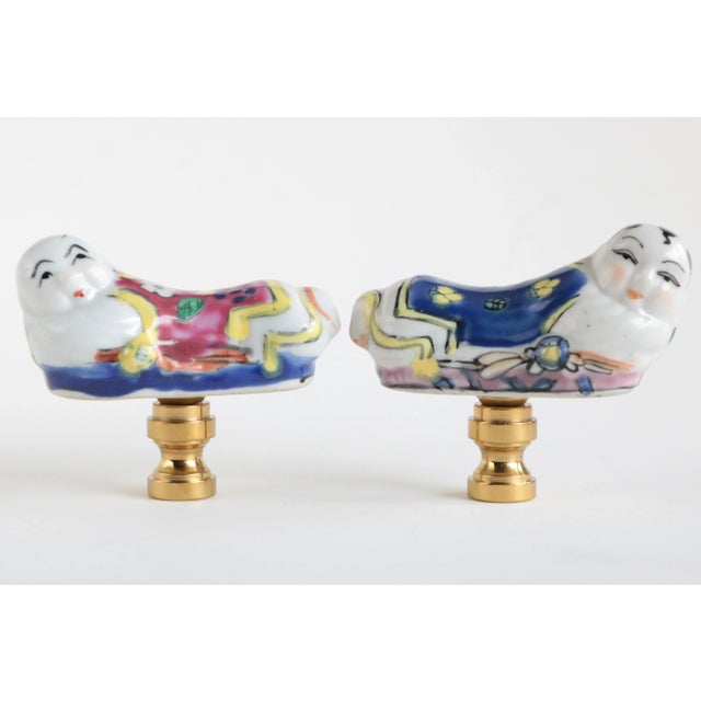 Pair of matching lamp finials crafted from vintage opium pillow-shaped porcelain figures. Plaster filled and mounted on...