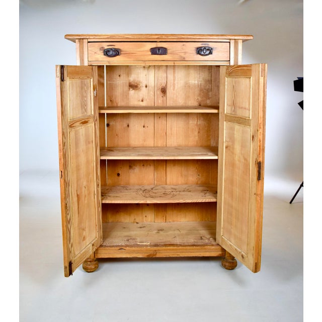 An Antique Vertigo pine cabinet featuring a single long drawer above a two-door cupboard cabinet with three removable...
