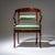Mahogany armchair with a rounded backrest and S-shaped armrests terminating in stylized dolphin heads. The seat and...