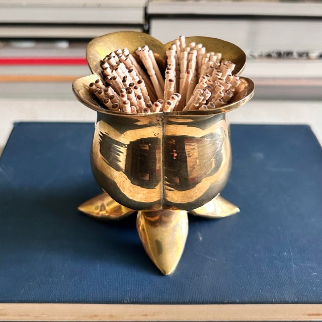 A sculptural vintage solid brass holder designed in the form of an open flower. Four curved petals form the rim, while a...