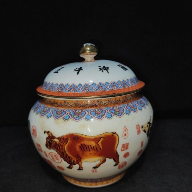 A beautiful pair of Chinese Famille Rose porcelain covered jars. The white ground is hand-painted with detailed oxen in a...