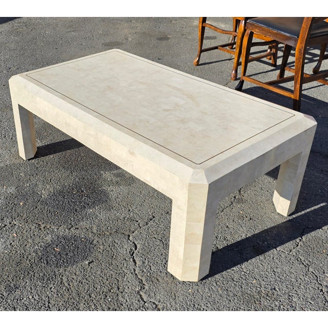 This Vintage Post Modern Tessellated Stone Coffee Table with Brass Inlay has mitered corners and a fully clad base, making...