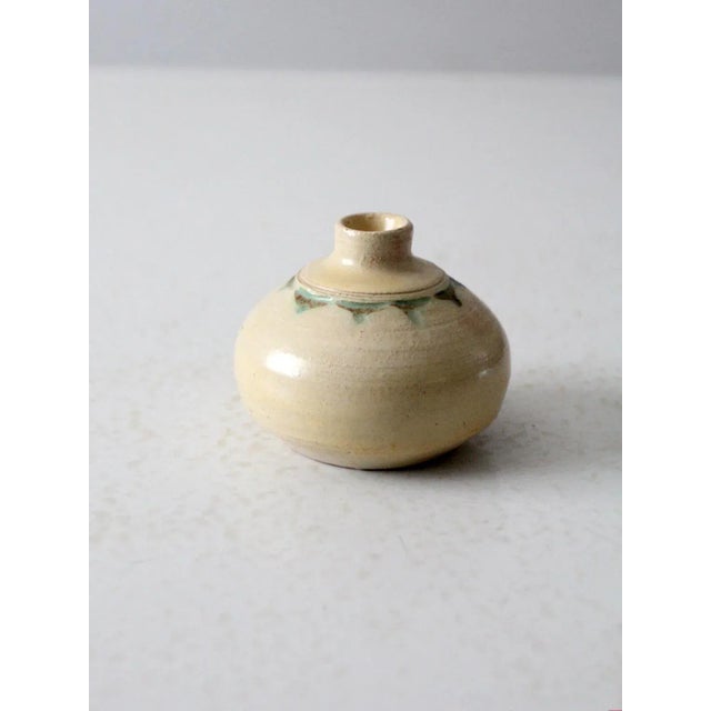 This is a vintage studio pottery vase. Signed by the artist, the handmade vase features a cream glaze with geometric green...